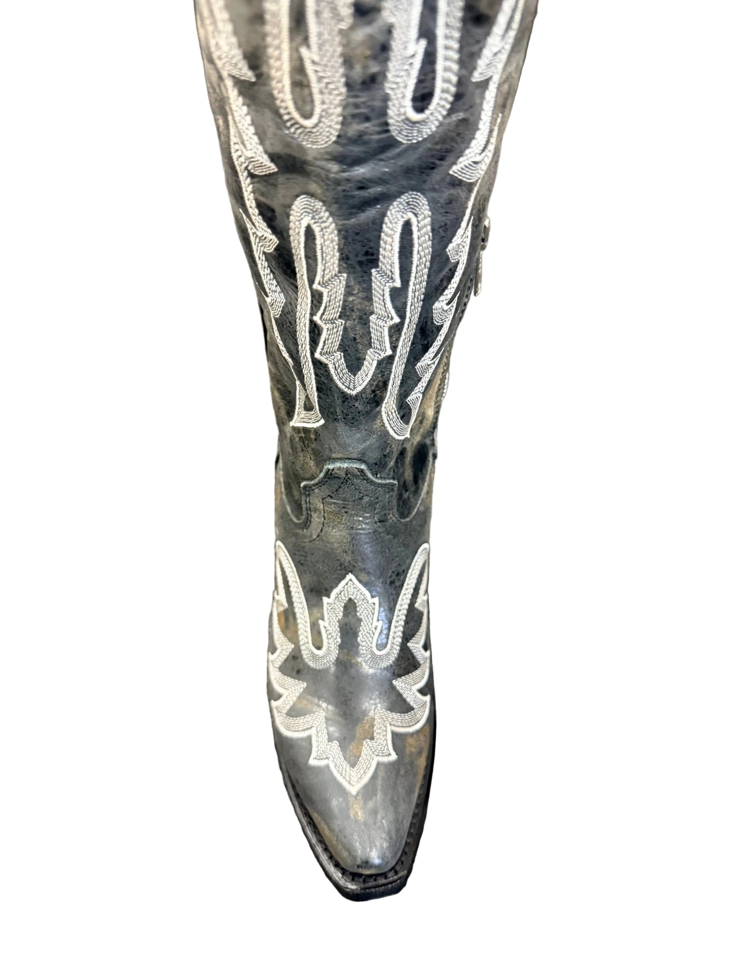 Black cowboy boot with white embroidery on a gray surface